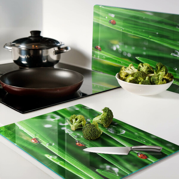 Planche à découper en verre Gouttes d'eau sur l'herbe avec des coccinelles