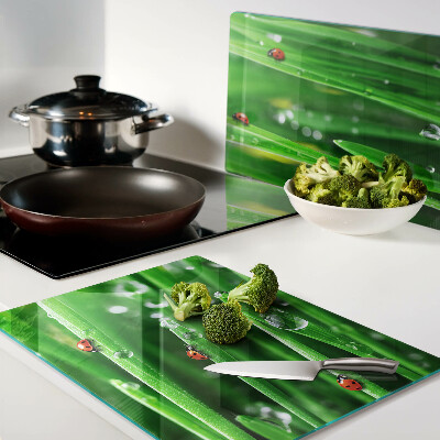Planche à découper en verre Gouttes d'eau sur l'herbe avec des coccinelles